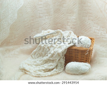 Basket of white yarn and knitwork on a gentle white background