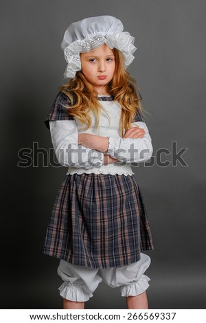 Girl in dress rustic vintage on a gray background crossed her arms and offended
