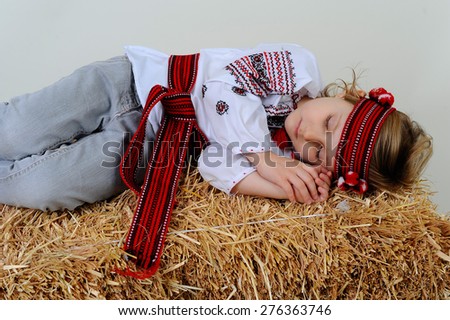 Ukrainian girl in national dress and jeans sleeps on a haystack