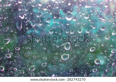 Raindrops on glass. Abstract backdrop. Color blurred view outside the window. Rainy weather  Wet home window with water drops.
