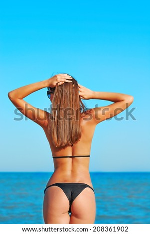 Sexy back of a beautiful woman on tropical beach in summer hot in small bikini