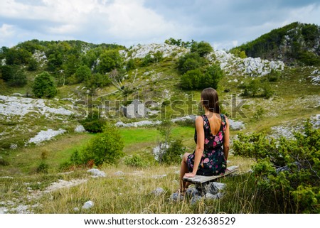 Beautiful young woman looking at the ruins of house. Montenegro, Europe.