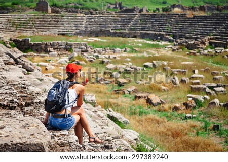 Pretty tourist woman with backpack at the ruins of ancient city of Perge near Antalya Turkey