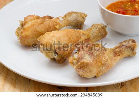 Fried fish sauce marinated chicken drumstick and sauce on white plate.