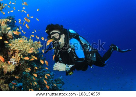 Underwater image of female Scuba Diver with tropical fish on a coral reef