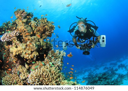Underwater Photographer scuba diving with camera on coral reef in ocean