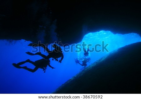 Silhouette of scuba divers in an underwater cave