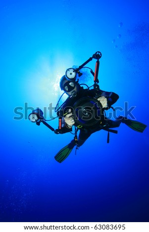 Underwater Photographer with digital SLR camera in a housing scuba dives on a coral reef