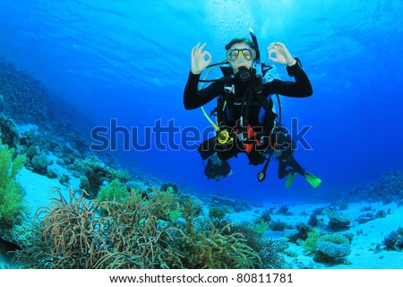 Female Scuba Diver swimming over a coral reef signals that she is Okay