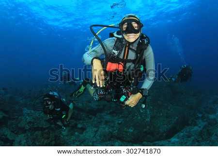 Female scuba diver exploring coral reef underwater with fish