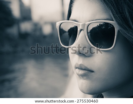 Black and white portrait of a teenage girl in colorful sunglasses close up