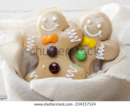 Smiling gingerbread men on white wooden background