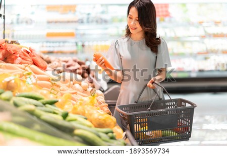 The young girl is choosing to buy vegetables at the supermarket