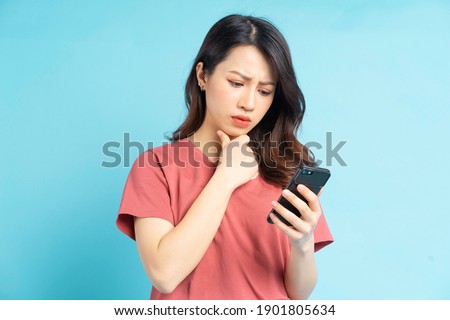 Beautiful Asian woman holding smartphone in hand with a thoughtful expression
 Foto stock © 