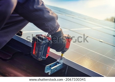 Solar panel technician with drill installing solar panels on roof.  technician in blue suit installing photovoltaic blue solar modules with screw. Electrician panel sun sustainable resources Photo stock © 