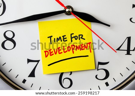 time for development on post-it stuck to a wall clock