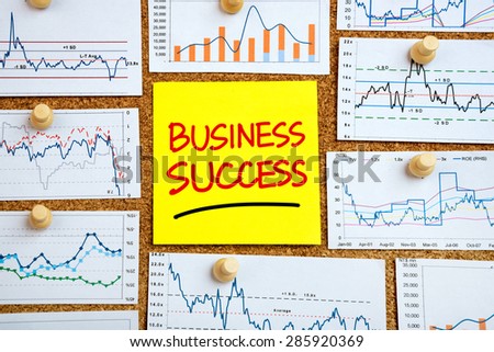 business success concept handwritten on post-it with financial graphs
