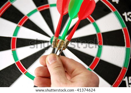 Darts in hand on dartboard background