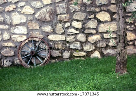An old wagon wheel on a stone wall