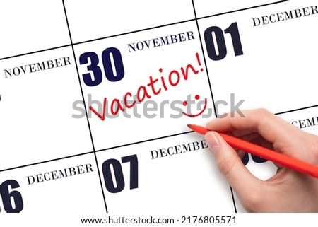 30th day of November. A hand writing a VACATION text and drawing a smiling face on a calendar date 30 November. Vacation planning concept. Autumn month, day of the year concept. Foto stock © 