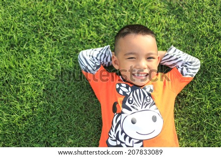 Little boy enjoying summer time lying on meadow green grass