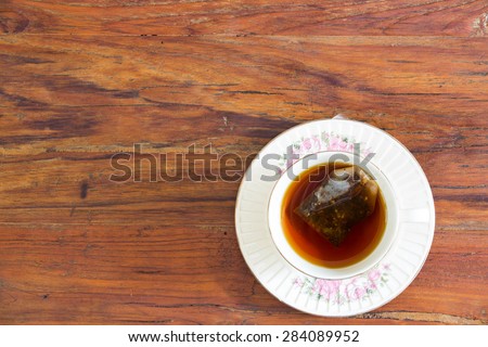 A cup of tea in English afternoon tea break on wooden table with tea bag in its.