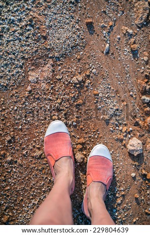Overhead photo of feet on a background of brown sand. Women feets. Exploring, travelling, tourism.