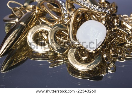 Heap of gold jewelry are reflected in a mirror