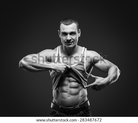 Bodybuilder showing his press. A man shows his abdominal muscles, raised his hand t-shirt. Press, muscles, show, bodybuilding. Sports guy.