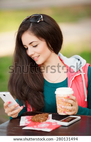Beautiful young woman cell phone and coffee at outdoors, smiling girl with smartphone an tea at street cafe, happy female doing selfie and sms outdoor, soft light series