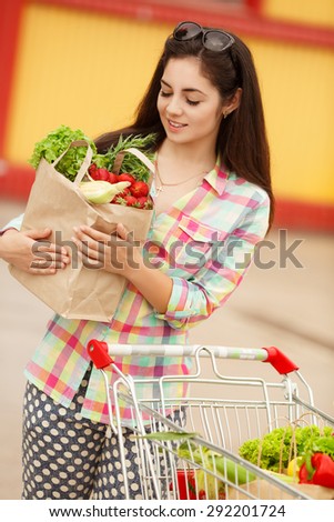 Beautiful shopping woman with vegetables, happy young girl in grocery shop with purchase bags full of organic vegetables, smiling female at supermarket buying food, instagam style filters, series