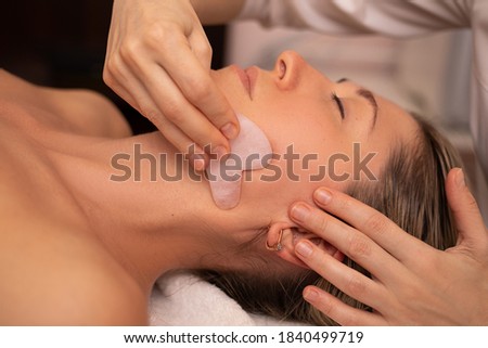 Young and beautiful woman during Chinese traditional massage - Gua Sha with stone. Close-up photo. Beauty treatment in SPA salon. Anti-aging skin care Foto stock © 