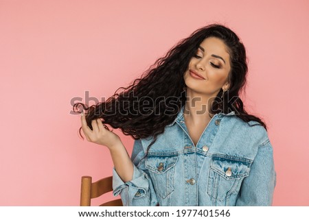 Beautiful young woman with curly dark hair admires its beauty and splendor. hair care and hair coloring concept Foto d'archivio © 