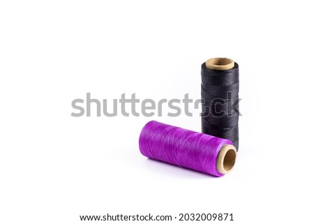 Purple and black spools of thread on a white background. Waxed purple and black threads for leather products. Black thread. Purple thread.