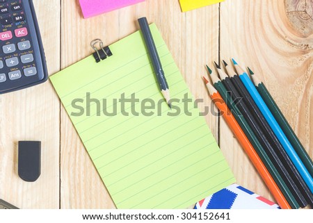 Notebook paper and school or office tools on wood table for background