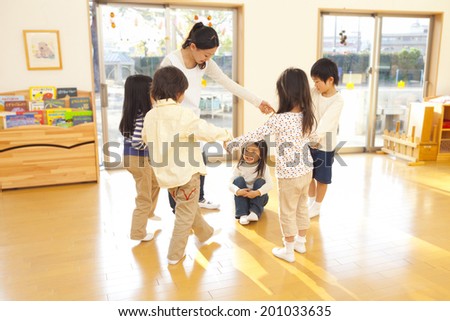 children and a nursery teacher dancing in a circle