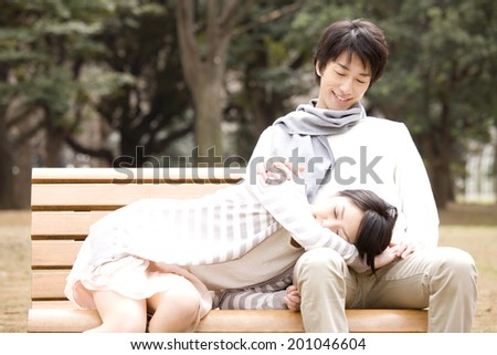 Girl in lying down by putting her head on the laps of a boyfriend