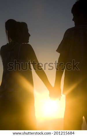 The silhouette of the couple holding hands in the evening