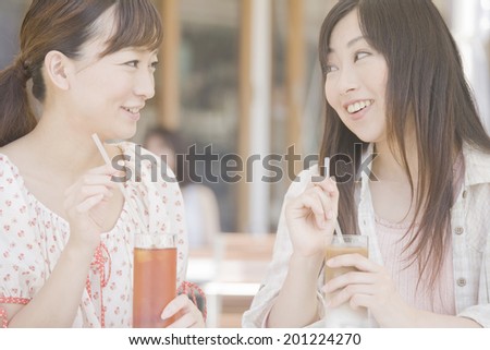 Two women drinking tea in open cafe