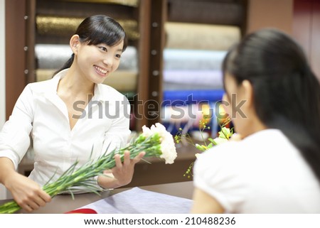 The female clerk in the flower shop and customers