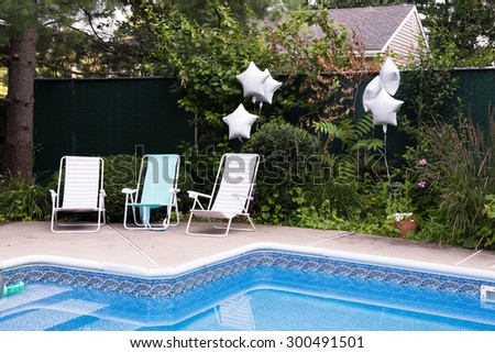 Empty loungers at the backyard pool waiting for party guests to arrive