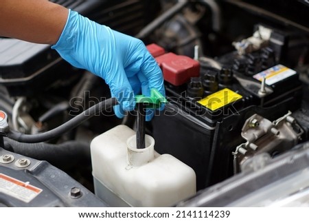 Mechanic's hand is opening bottle of water in car engine to Check auto car's coolant level. Concept : Checking and maintenance car service.                              Foto stock © 
