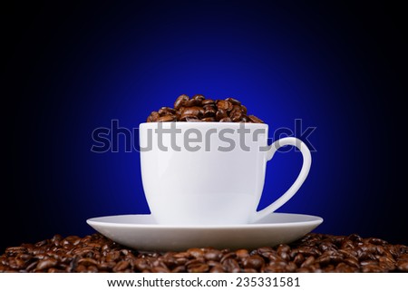 coffee beans in a white cup on a black background with a blue halo