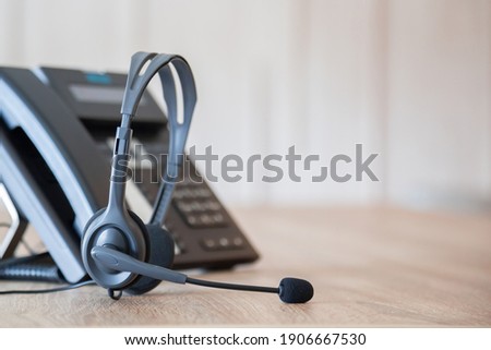 Communication support, call center and customer service help desk. VOIP headset on telephone keyboard.