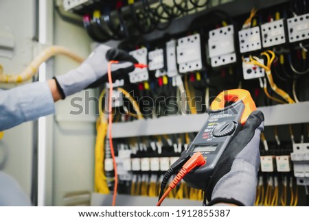 Electrical engineers test electrical installations and wiring on protective relays, measuring them with a multimeter. Photo stock © 