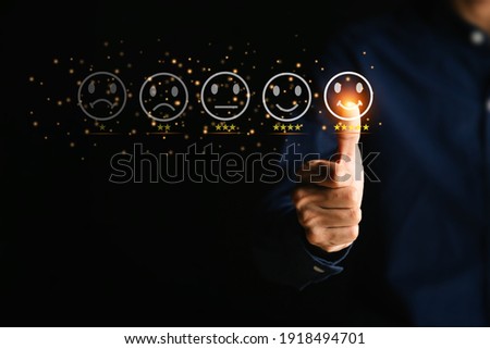 Customer service and Satisfaction concept ,Businessman are touching the virtual screen on the happy Smiley face icon to give satisfaction in service. 5-star rating very impressed.