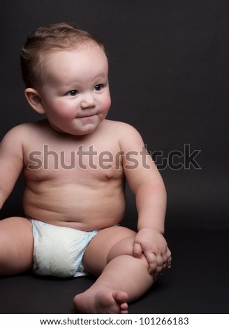 A one year old baby through a non-verbal communication  process showing a positive gesture with a slight artificial smile