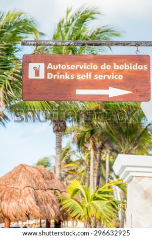 Drinks self service sign in both English and Spanish showing direction to a bar on a  tropical resort. Mexico, May 2015.