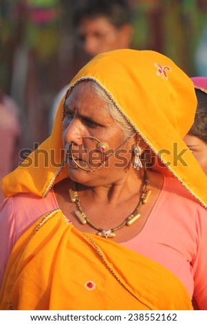 PUSHKAR, INDIA - NOV 28: Senior Indian woman with yellow veil and a big nose circle walking in Pushkar Fair in November 28 2012
