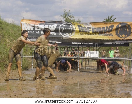 SIGNA, ITALY - MAY 9 2015: People passing  under the wires during the Inferno Run Mud Race competition, while civil protection splash water to them